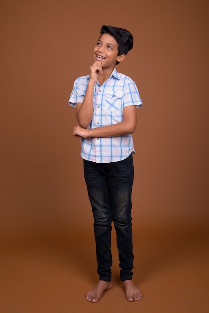 Young Indian boy wearing checkered shirt against brown background