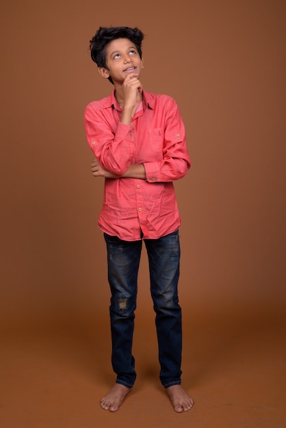 Young Indian boy wearing smart casual clothing against brown background