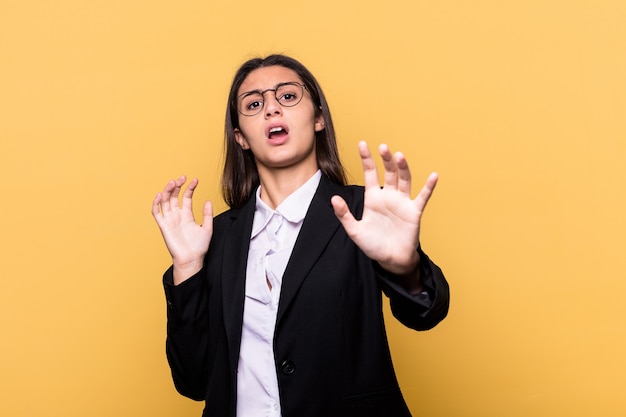 Young Indian business woman isolated on yellow background being shocked due to an imminent danger