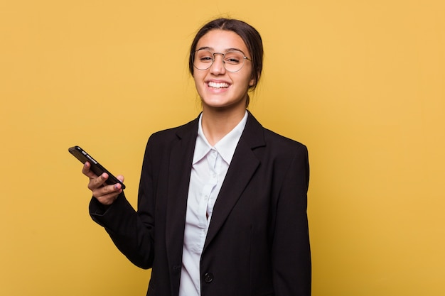 Young indian business woman talking on phone isolated on yellow wall