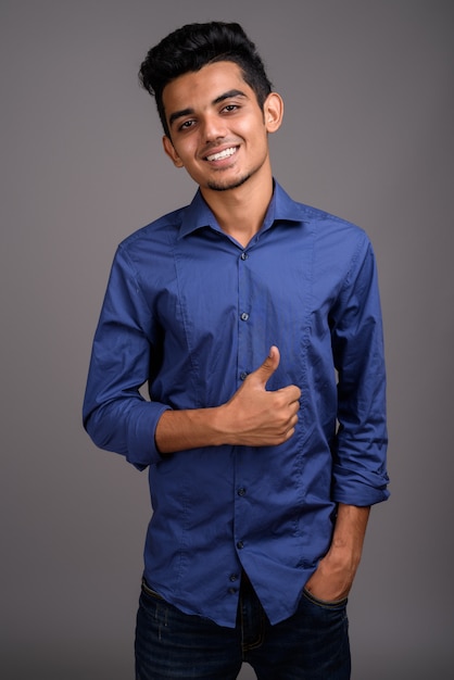 Young Indian businessman against gray wall