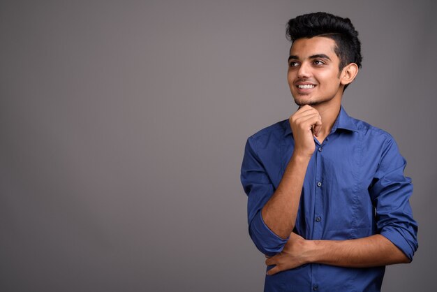 Young Indian businessman against gray wall