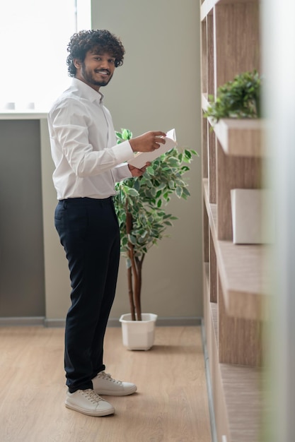 Young indian businessman choosing a book from the shelf