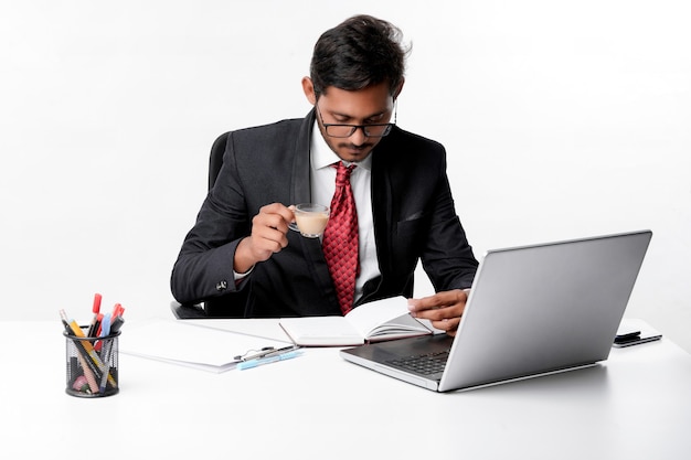 Young indian businessman working on laptop and drinking tea at office.