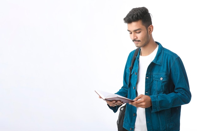 Young Indian college student holding dairy in hand on white background.