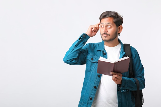 Young Indian college student holding diary in hand on white background.