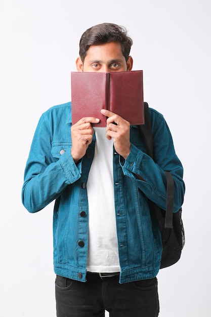 Young Indian college student holding diary in hand on white background.