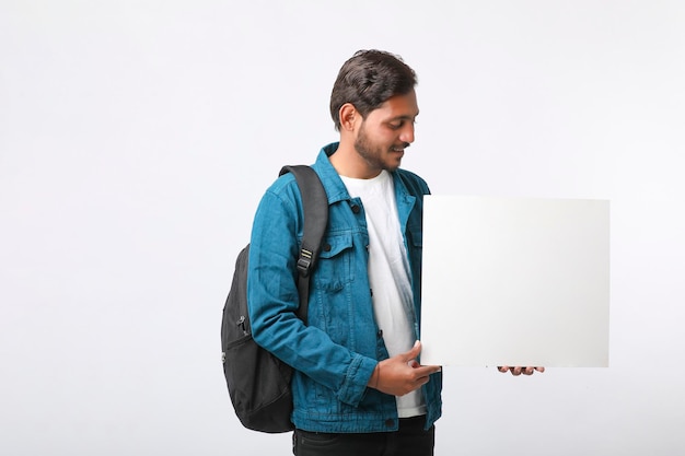 Young indian college student showing blank sign board on white background.