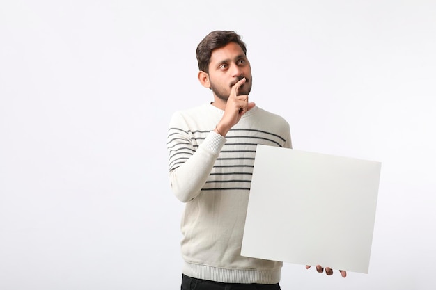 Young Indian college student showing blank signboard on white background.