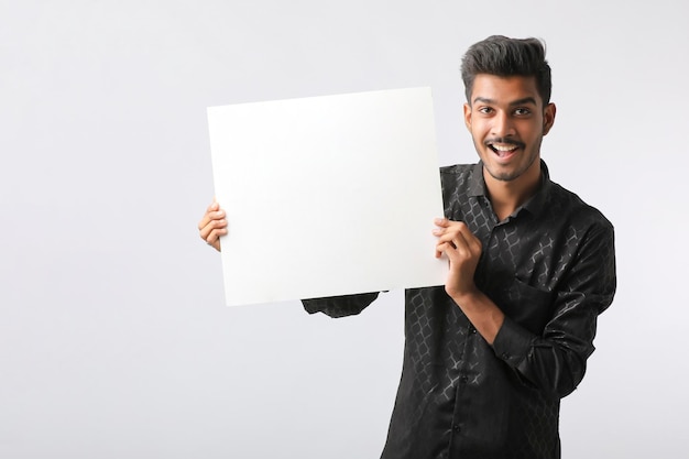 Young Indian college student showing blank signboard on white background.