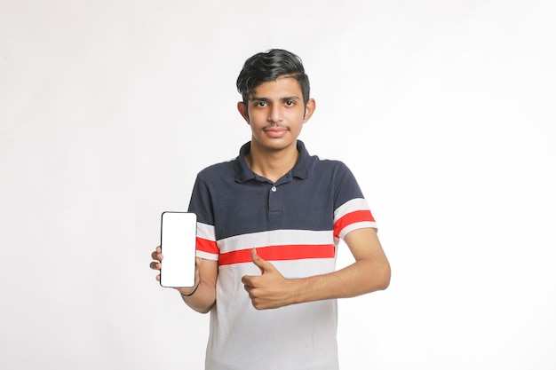白い背景の上のスマートフォンの画面を表示している若いインドの大学生。