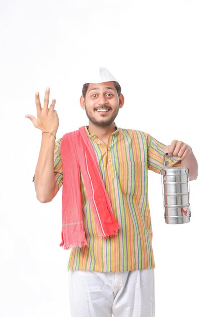 Young indian common man in traditional wear holding tiffin box in hand on white background.