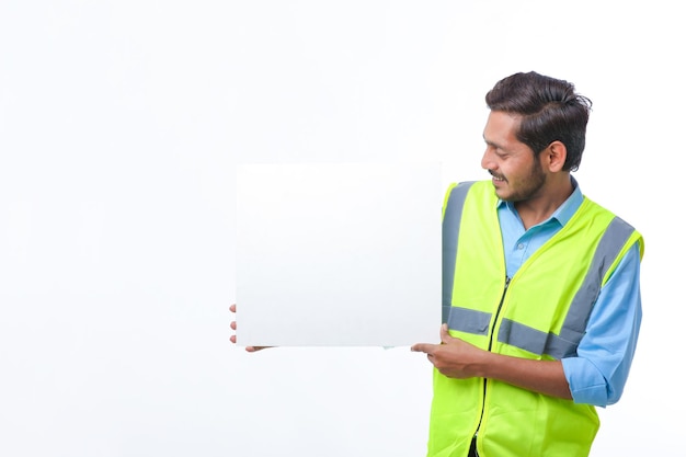 Young indian Construction Worker Showing Empty Poster Board on White Background.