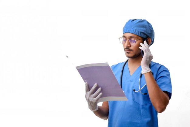 Young indian Doctor checking out some reports and talking on smartphone.