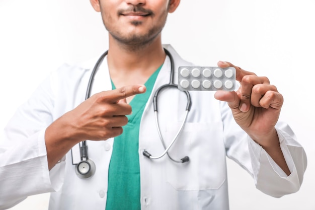 Young indian doctor holding medicine strip in hand.