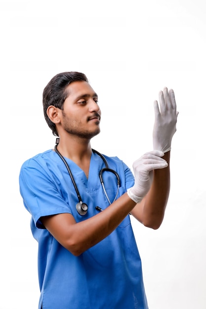 白い背景で隔離の保護手袋を着用して若いインドの医師。