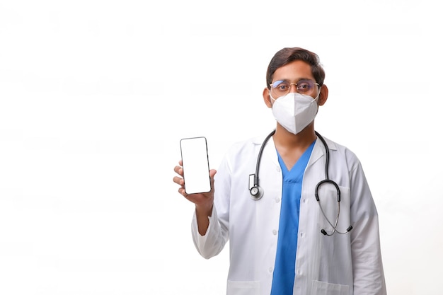 Young indian doctor showing smartphone screen over white background.