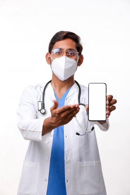 Young indian doctor showing smartphone screen over white background.