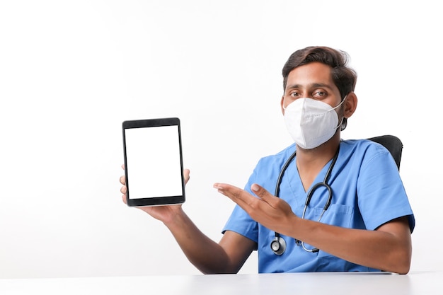 Young indian doctor showing tablet screen at clinic.