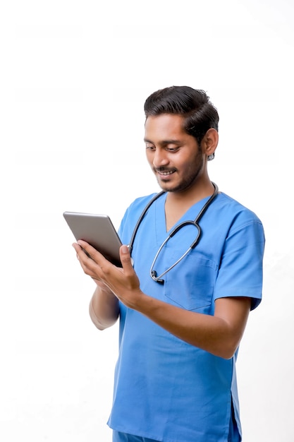 白い背景の上にスマートフォンを使用して若いインドの医師。