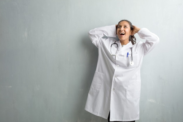 驚いてショックを受けて、広い目で見ている壁に対して若いインド人医師女性