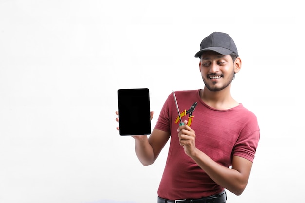 Young indian electrician holding tools in hand and showing smartphone.