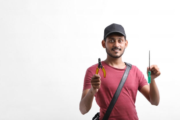 Young indian electrician holding tools in hand and standing over white background.