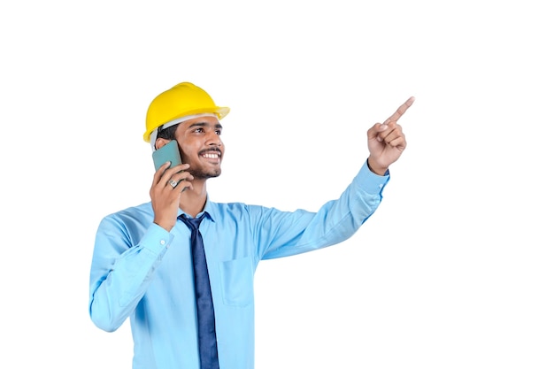 Young indian engineer or construction site worker using smartphone.