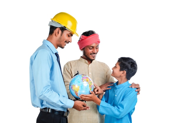 Young indian engineer showing some detail to farmer and his child in world globe map.