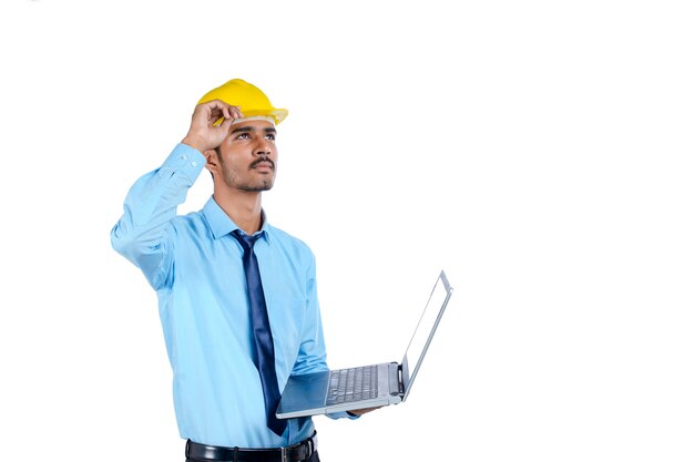 Young Indian engineer in uniform and using laptop on white background.