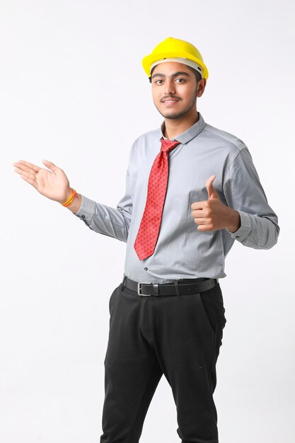 Young Indian engineer wearing yellow color hard hat and giving successful gesture.