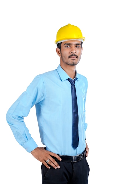 노란색 하드 모자를 쓰고 성공적인 제스처를 주는 젊은 인도 엔지니어.