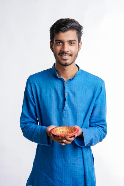 Young Indian in ethnic wear and holding oil lamp in Hand. celebrating Diwali festival.