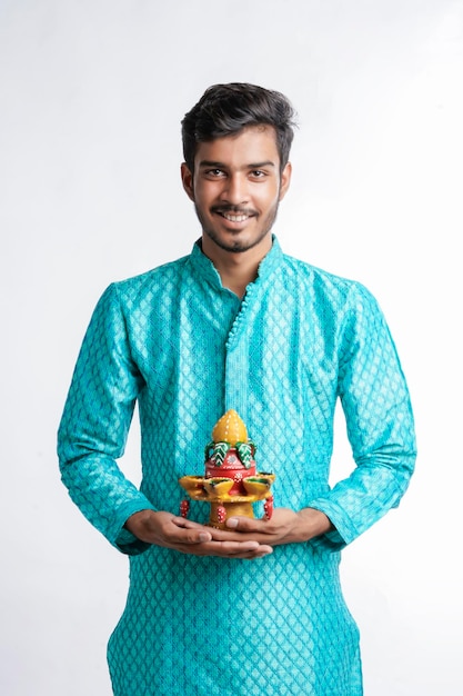 Young Indian in ethnic wear and holding oil lamp in Hand. celebrating Diwali festival.