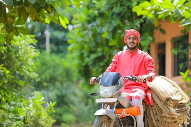 若いインドの農民はバイクで荒布袋を収集します