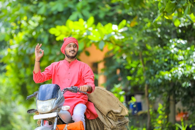 Young indian farmer collect sackcloth bag on motor bike