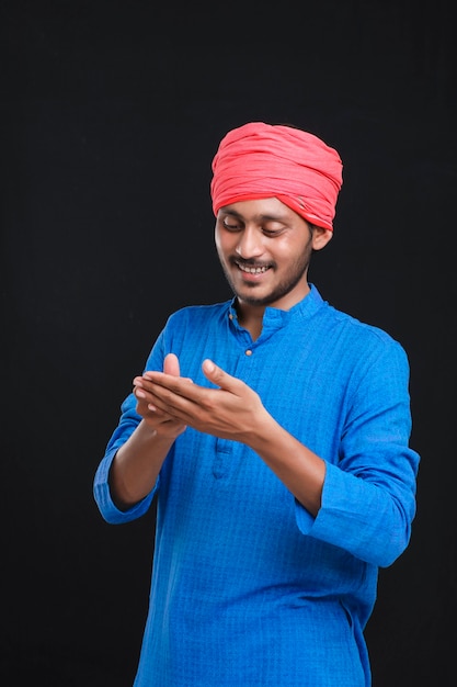 Young indian farmer giving expression on dark background.