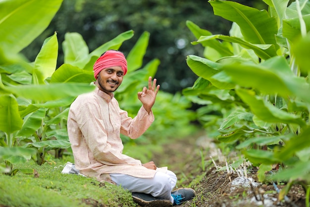 Молодой индийский фермер на поле сельского хозяйства зеленых бананов.