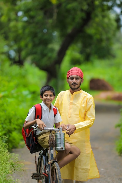 Young indian farmer and his son going to school on cycle