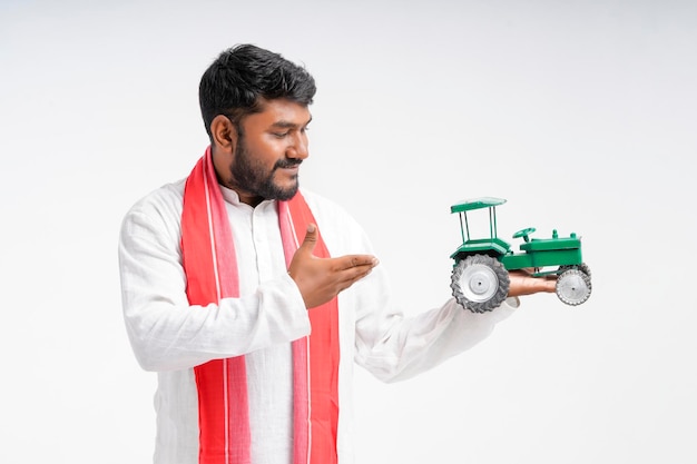 Young indian farmer holding tractor toy and showing money