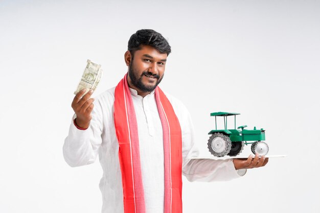 Young indian farmer holding tractor toy and showing money