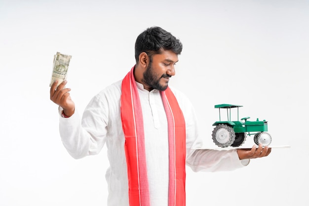 Young indian farmer holding tractor toy and showing money