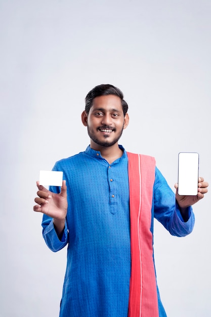 Young indian farmer showing card and smartphone on white background