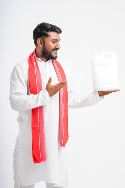 Young indian farmer showing fertilizer bottle on white background