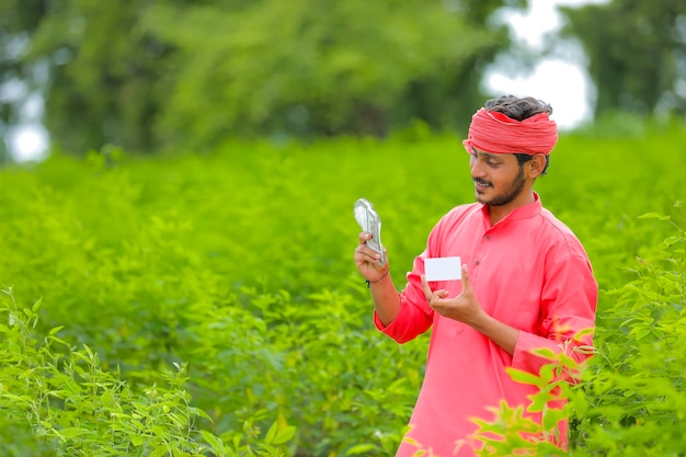 Young indian farmer showing money and a card