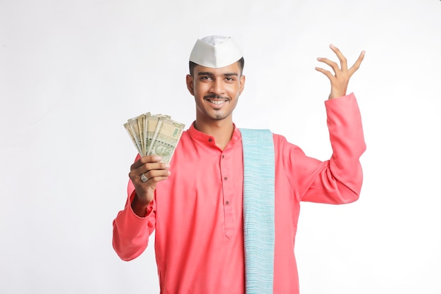 白い背景にお金を示す若いインドの農夫。