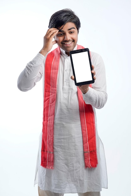 Young indian farmer showing smart phone or tablet and giving expression on white background