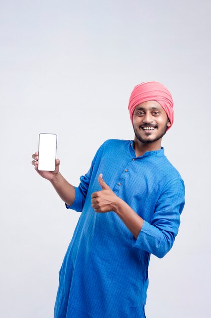 Young indian farmer showing smartphone and giving expression on white background.