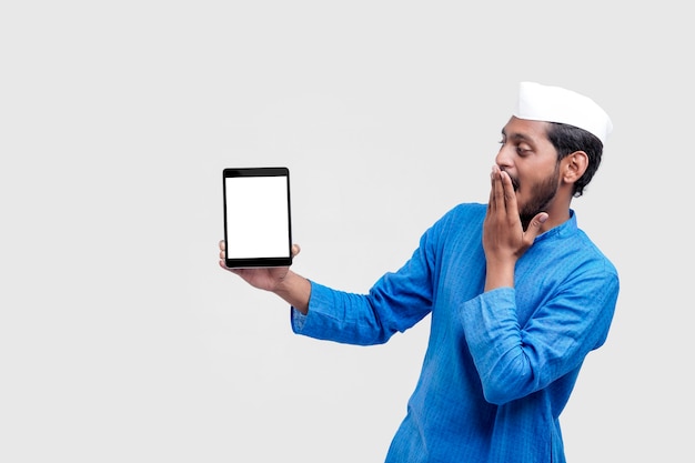 Young indian farmer showing smartphone and giving expression on white background.