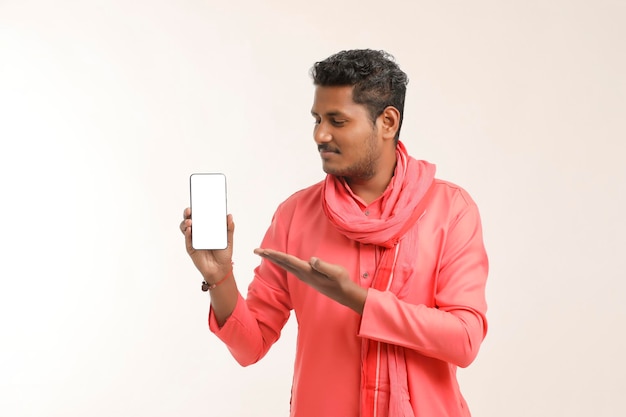 Young indian farmer showing smartphone and giving expression on white background.